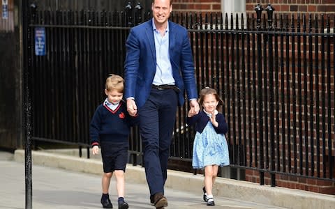 The Duke of Cambridge grins at the cameras, flanked by his eldest son Prince George and a waving Princess Charlotte - Credit: DASA