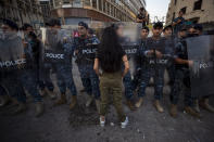 An anti-government protester stands in front of riot police after protesters removed a concrete wall that was installed by security forces to prevent them from reaching the government palace in Beirut, Lebanon, Thursday, July 2, 2020. Major retailers in Lebanon announced Thursday they will temporarily close in the face of an increasingly volatile currency market and their inability to set prices while the local currency tumbles before the dollar. (AP Photo/Hassan Ammar)