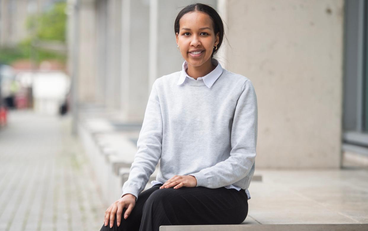 Nimo Mohamed sitting outside her office building. She did a degree in accounting and finance, but has since retrained as a software engineer