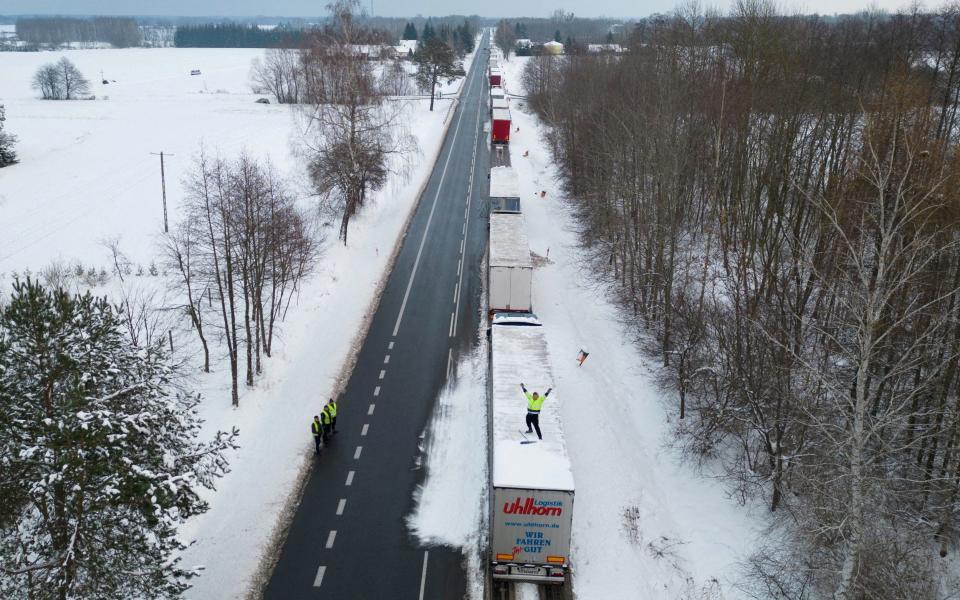 A truck driver from Ukraine waves from his truck roof while waiting in a long queue to cross the Polish-Ukrainian border