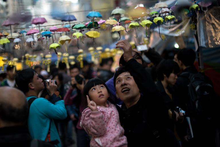 A man and his daughter pose for photos next to an installation of paper umbrellas -- symbols of the pro-democracy protests in Hong Kong -- in the Causeway Bay district of Hong Kong on December 14, 2014