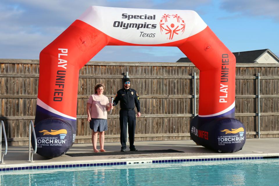 Lindsey Fowler and Sgt. Sheldon West carry the Special Olympics torch to the pool's edge to mark the start of the annual Special Olympics Polar Plunge at Amarillo Town Club on Hillside Saturday morning.