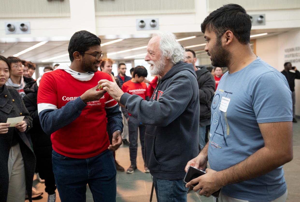 Nobel laureate Pierre Agostini hands back a rupee with his autograph Wednesday to Suriyaa Ramanathan, a graduate student in condensed matter theory, at the Ohio State University's Physics Research Building on the Columbus campus. Agostini, an Ohio State professor emeritus, donated his replica Nobel Prize to the university for display in the building. Agostini was awarded the prize "for experimental methods that generate attosecond pulses of light for the study of electron dynamics in matter."