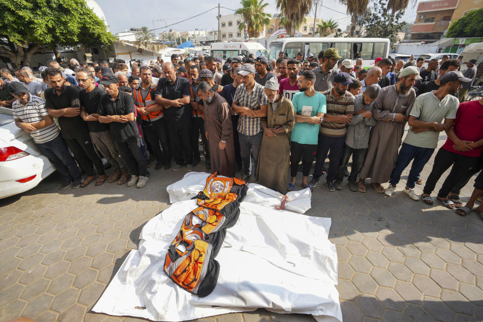 Palestinians pray next to the bodies of the three civil defense members killed in the Israeli bombardment of Nuseirat refugee camp, at al-Aqsa Martyrs Hospital in Deir al Balah, central Gaza Strip, Friday, June 28, 2024. (AP Photo/Abdel Kareem Hana)