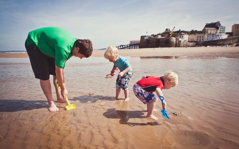 Father and sons playing on the beach while on vacation