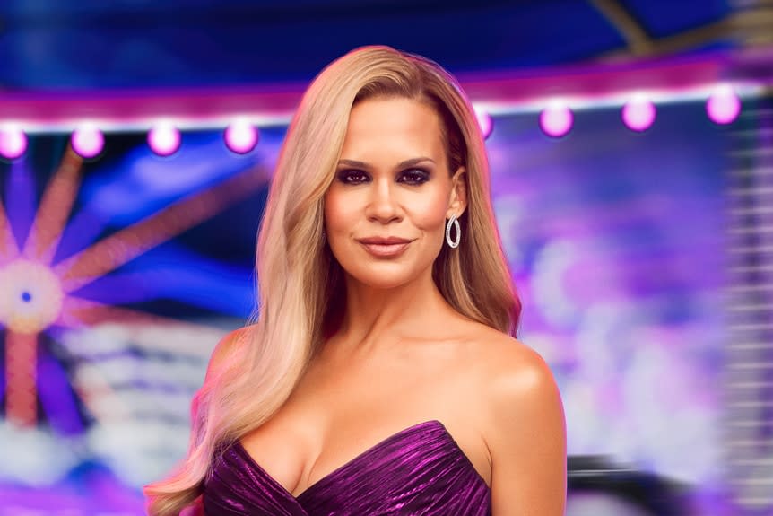 Jackie Goldschneider wearing a purple gown in front of a carnival backdrop.