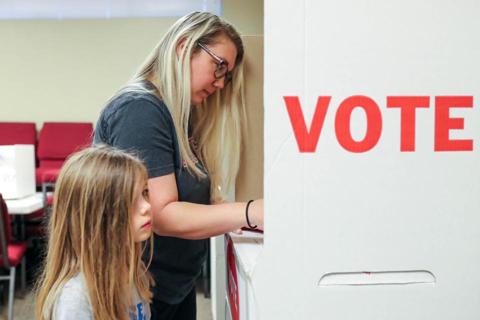Katie Weir fills out her ballot with her daughter Quinn as voters take to the polls at Westwood Church of Christ in Edmond, Okla., on Tuesday, April 4, 2023.