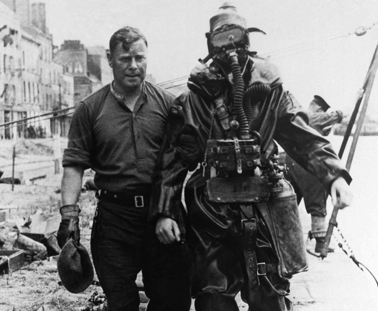 A diver of the British Royal Navy is walking down a pier of Cherbourg harbor on