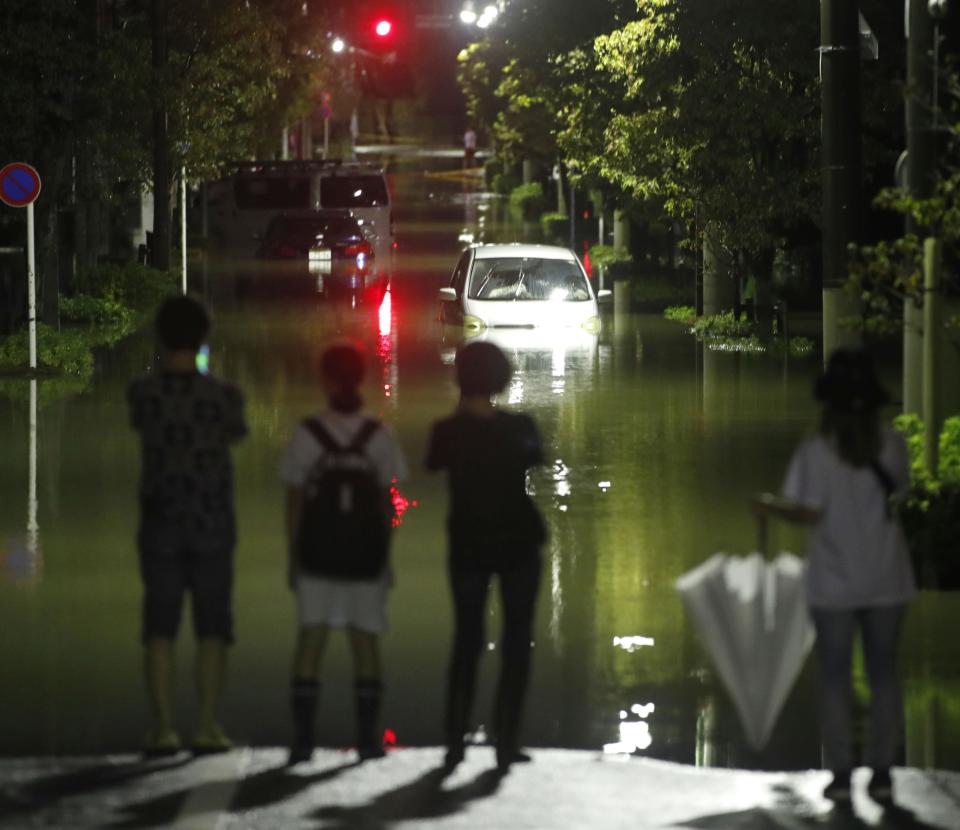 People look at the submerged residential area hit by Typhoon Hagibis, in Tokyo, Saturday, Oct. 12, 2019. A heavy downpour and strong winds pounded Tokyo and surrounding areas on Saturday as a powerful typhoon forecast as the worst in six decades approached landfall, with streets and train stations deserted and shops shuttered.(Kyodo News via AP)