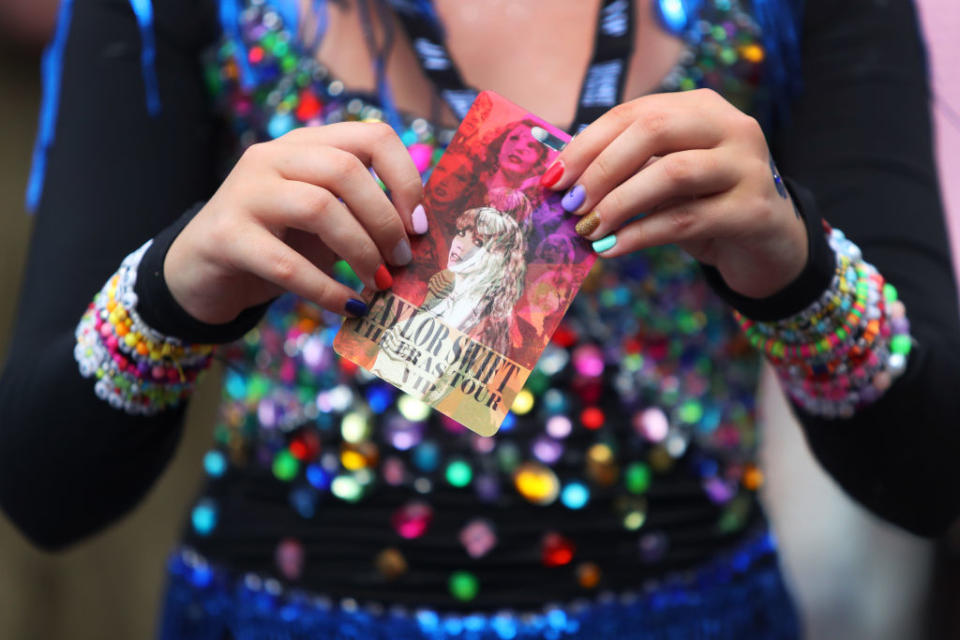 Person holding a Taylor Swift Eras Tour ticket with beaded bracelets