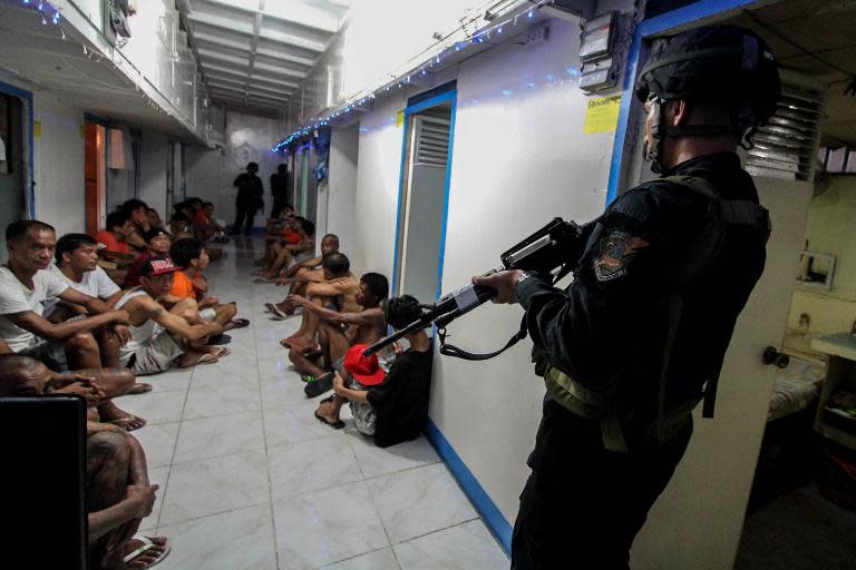 Photo taken on December 16, 2014 shows National Bureau of Investigation (NBI) operatives rounding up inmates inside New Bilibid Prison in Muntinlupa, south of Manila