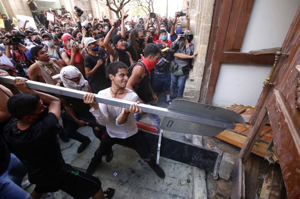 Demonstrators smash a door during a protest following the death of a young man while in police custody in Guadalajara, Mexico: AFP via Getty Images