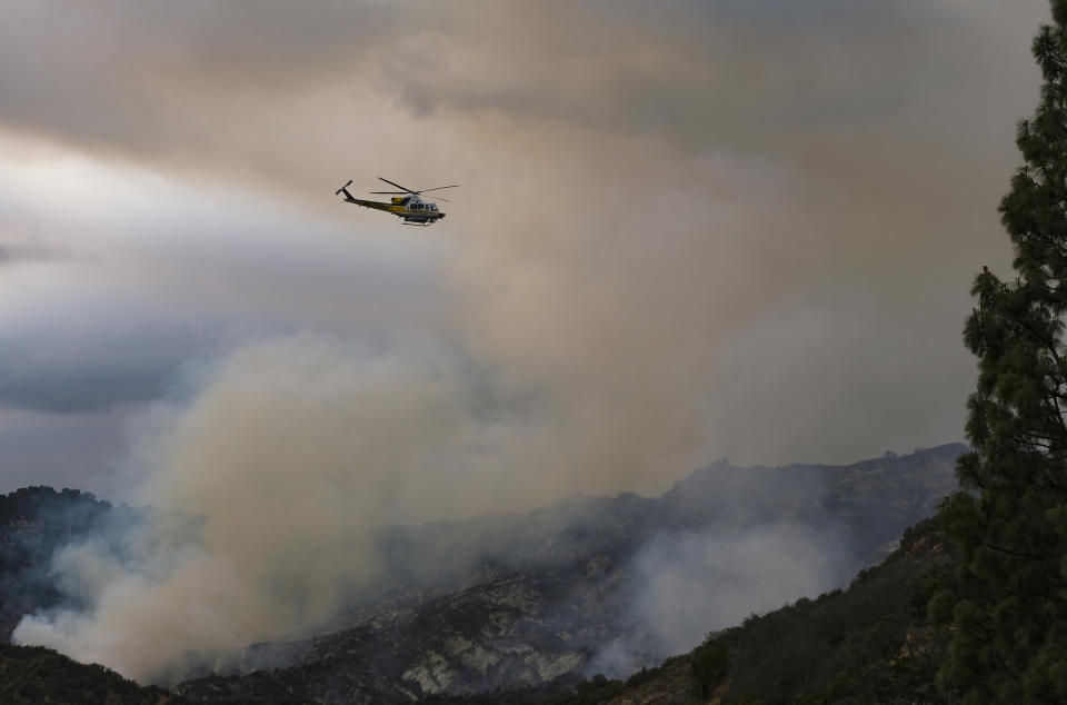 A helicopter flies over a brush fire scorching the Pacific Palisades area of Los Angeles, Sunday, May 16, 2021. (AP Photo/Ringo H.W. Chiu)