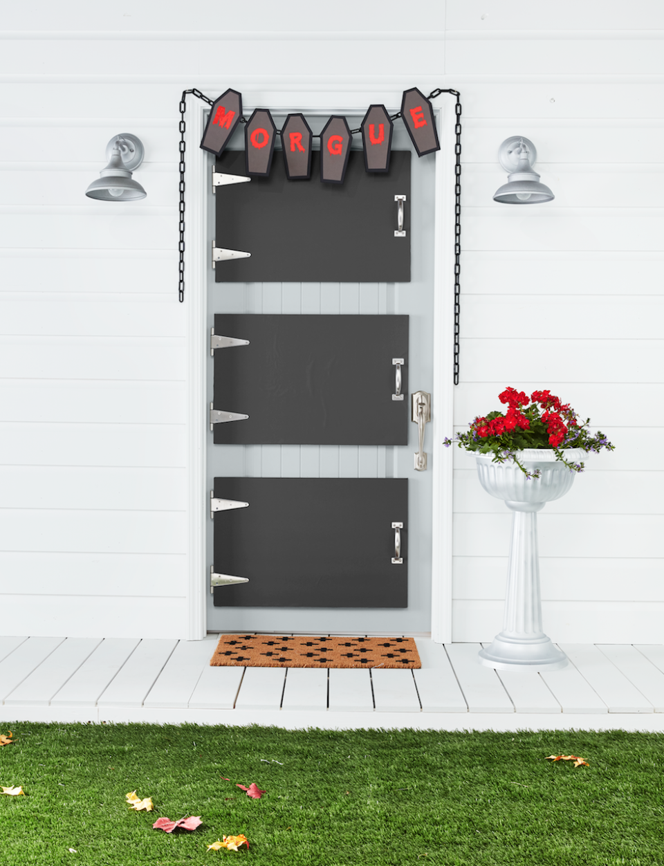 <p>Although there are many ways to turn your door into a spooky entrance, we think this morgue idea is the creepiest of them all. </p><p><strong>Make the Morgue Door</strong><strong>: </strong>Attach three precut 20- by 30-inch pieces of foam core together with spray adhesive. Attach a piece of black paper, cut to size, to the top piece of foam core using spray adhesive. Insert the rectangular piece of two 6-inch stainless steel T-hinges between the first and second pieces of foam core on one of the short sides; "screw" in place. Place a 6 1/2-inch handle on the opposite side; "screw" in place. Cover exposed edges of the foam core with silver duct tape, folding any excess to the back. Make two more doors. Adhere to house door with heavy- duty self-adhesive Velcro. Cut five coffin shapes from black and gray kraft paper. Paint letters on gray coffins with red acrylic paint to spell "morgue" and attach to black coffins with double-sided tape. Hang a plastic chain above the door and attach coffin cutouts with hot-glue. Add plastic pedestal planter painted Titanium Silver by Rust-Oleum and "Swiss Cross" doormat.</p>