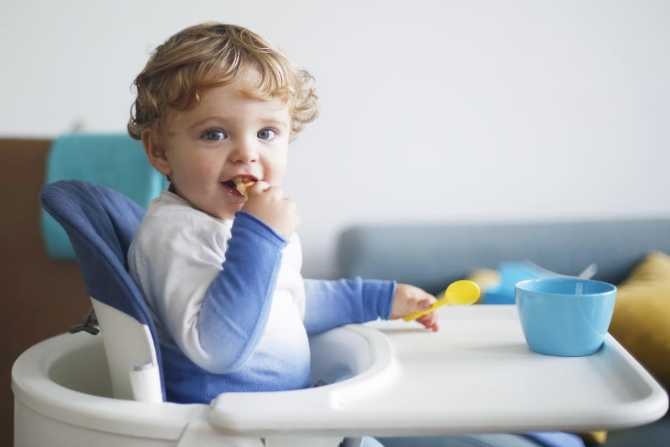 A 15 months old boy eating in his high chair