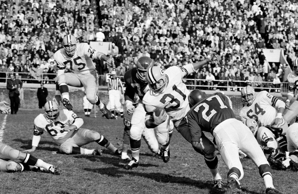 Action in the first period of the game between the Philadelphia Eagles and Green Bay Packers in Philadelphia, Nov. 11, 1962. Packers fullback Jim Taylor (31) makes a short gain as he is tackled by Eagles' Irv Cross (27) and Packers tackle Forrest Gregg (75) vaults over teammate Fred Thurston (63) in effort to help. Closing in from behind Taylor is Eagles' Riley Gunnels (74). (AP Photo/Bill Ingraham)