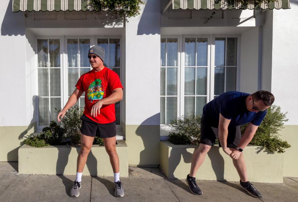 Two people stretching and warming up outside a building.