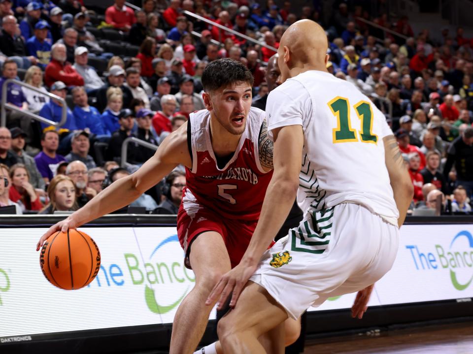 Kruz Perrott-Hunt #5 of the South Dakota Coyotes looks to drive to the basket against Jacari White #11 of the North Dakota State Bison at the 2023 Summit League Basketball Championship at the Denny Sanford Premier Center in Sioux Falls, South Dakota. (Photo by Dave Eggen/Inertia)