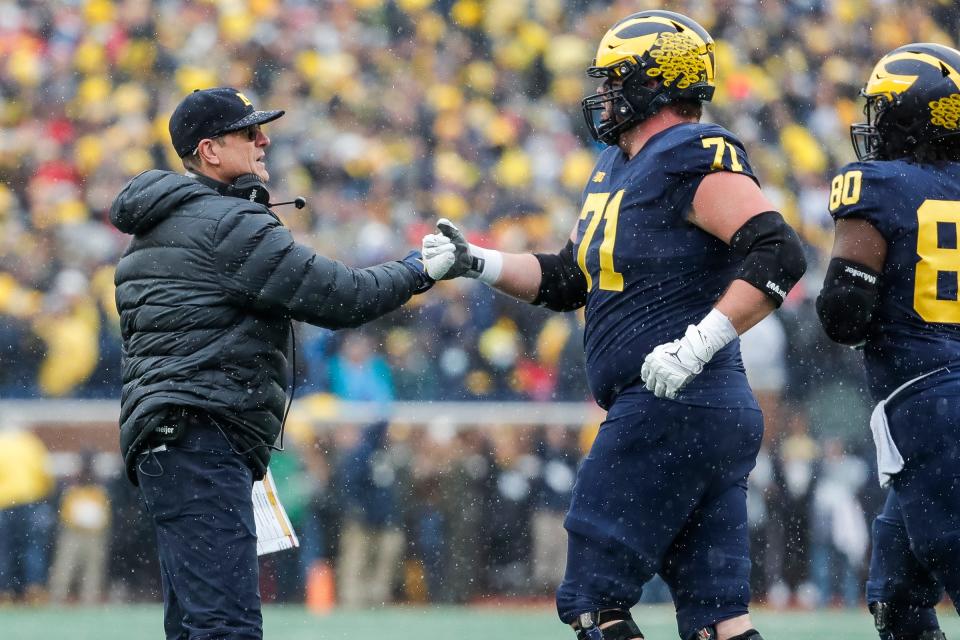 Michigan head coach Jim Harbaugh fist bumps offensive lineman Andrew Stueber during the first half against Ohio State at Michigan Stadium in Ann Arbor on Saturday, Nov. 27, 2021.