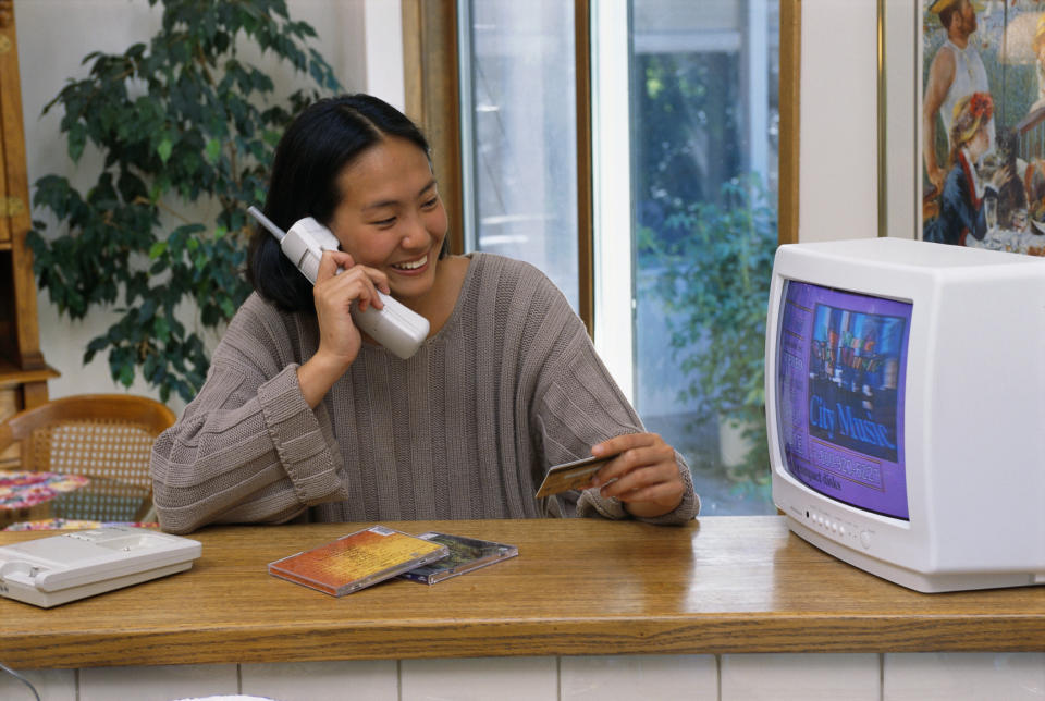 A person on the phone in front of a small white TV on the counter