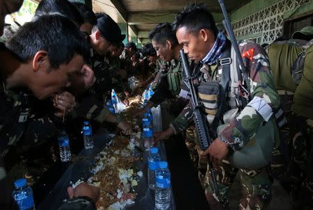 Soldiers gather to have a meal inside a compound after government troops cleared the area. REUTERS/Romeo Ranoco