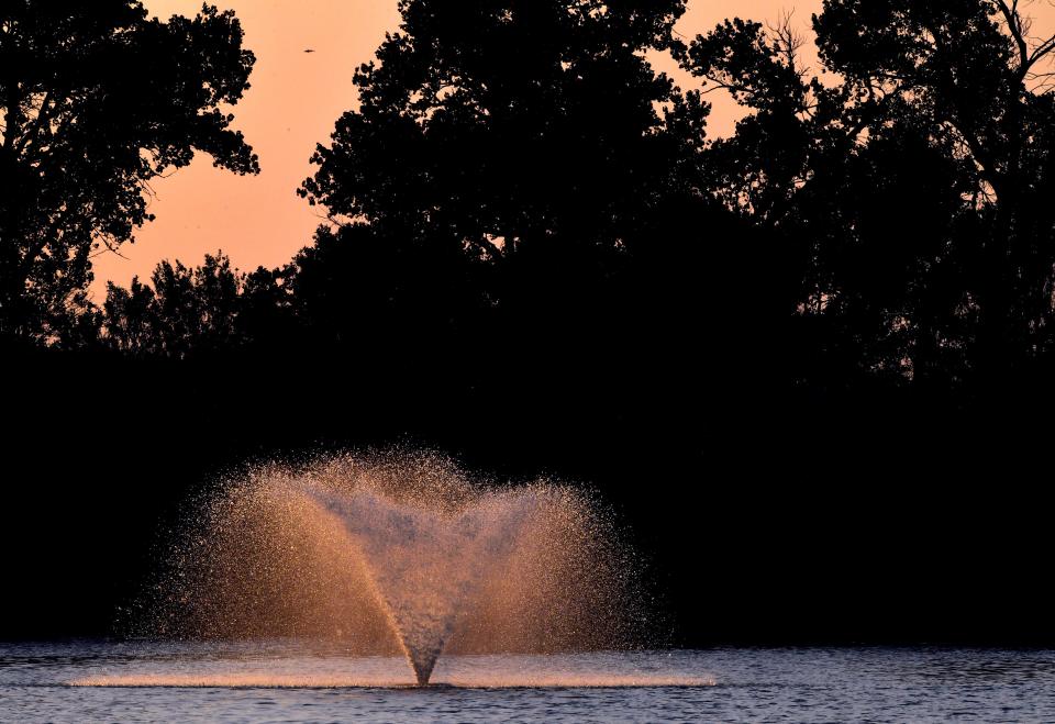 The setting sun illuminates a fountain in Tittle Lake July 10, 2020.