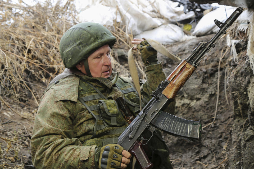 FILE - A serviceman holds his Kalashnikov gun as he guards at the line of separation near Sentianivka, Luhansk region, controlled by Russia-backed separatists, eastern Ukraine, Dec. 9, 2021. Amid fears of a Russian invasion of Ukraine, tensions have also soared in the country’s east, where Ukrainian forces are locked in a nearly eight-year conflict with Russia-backed separatists. A sharp increase in skirmishes on Thursday Feb. 17, 2022 raised fears that Moscow could use the situation as a pretext for an incursion. (AP Photo/Alexei Alexandrov, File)
