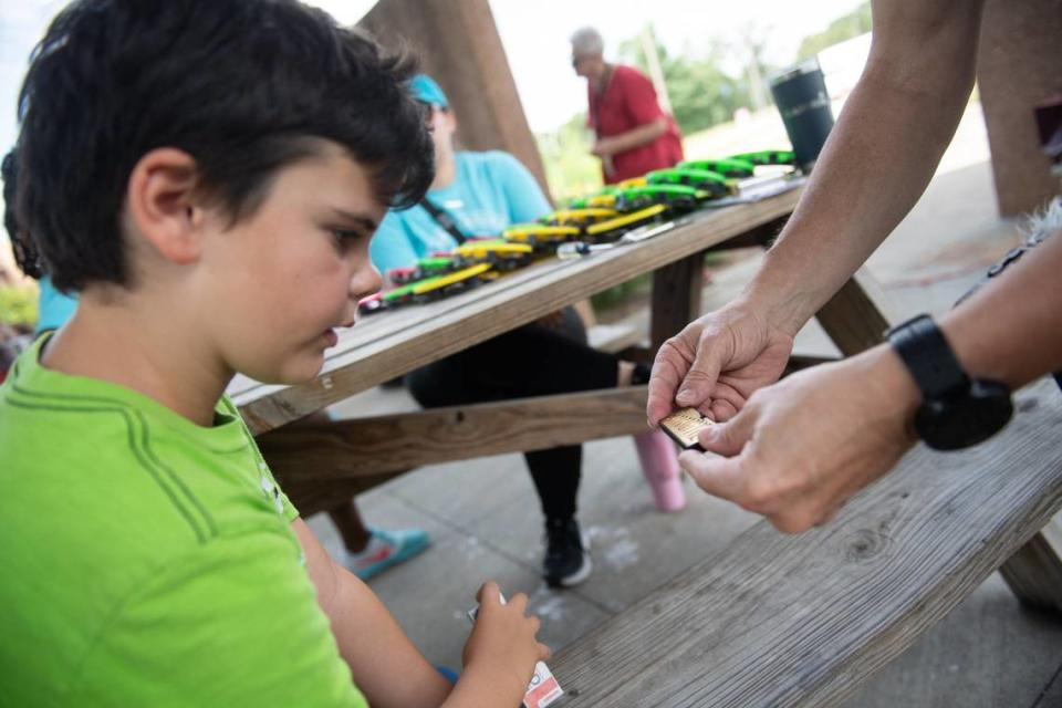 Schenke shows Garrett Lehman the interior plate of a simple harmonica at a beginners workshop during Make Music Day.