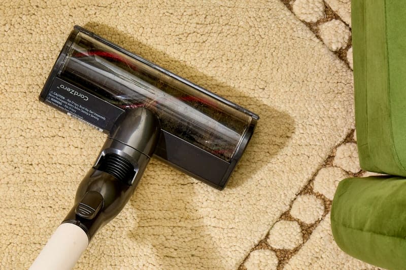 Overhead shot of a cream colored rug being vacuumed.
