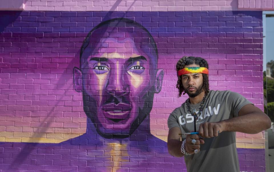 Artist Joshua "Prophet Josh" McCadney stands by one of two Kobe murals he created on Melrose Avenue.