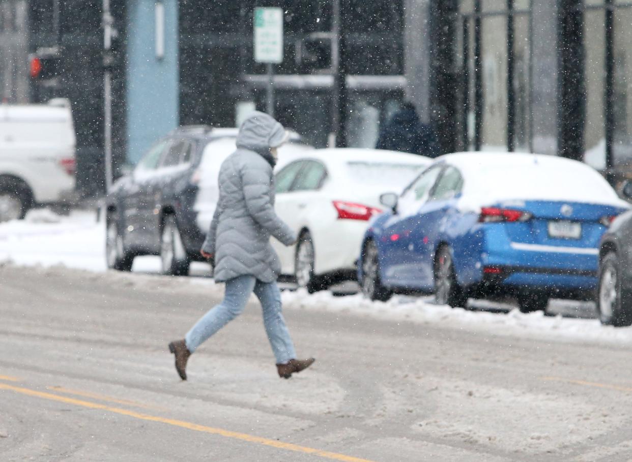 A bundled-up person runs across Washington Street east of Main Street on Friday, Jan. 12, 2024, in downtown South Bend. The snowfall this weekend will give way to single digit temperatures and sub-zero windchills to start next week.