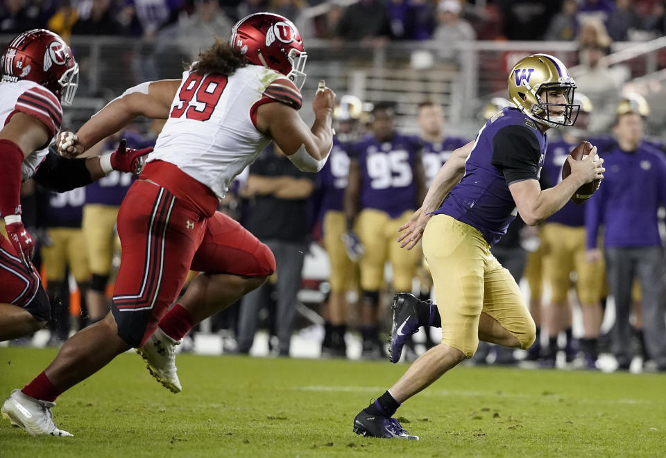 Washington quarterback Jake Browning, right, runs away from Utah defensive tackle Leki Fotu (99) during the first half of the Pac-12 Conference championship NCAA college football game in Santa Clara, Calif., Friday, Nov. 30, 2018. (AP Photo/Tony Avelar)