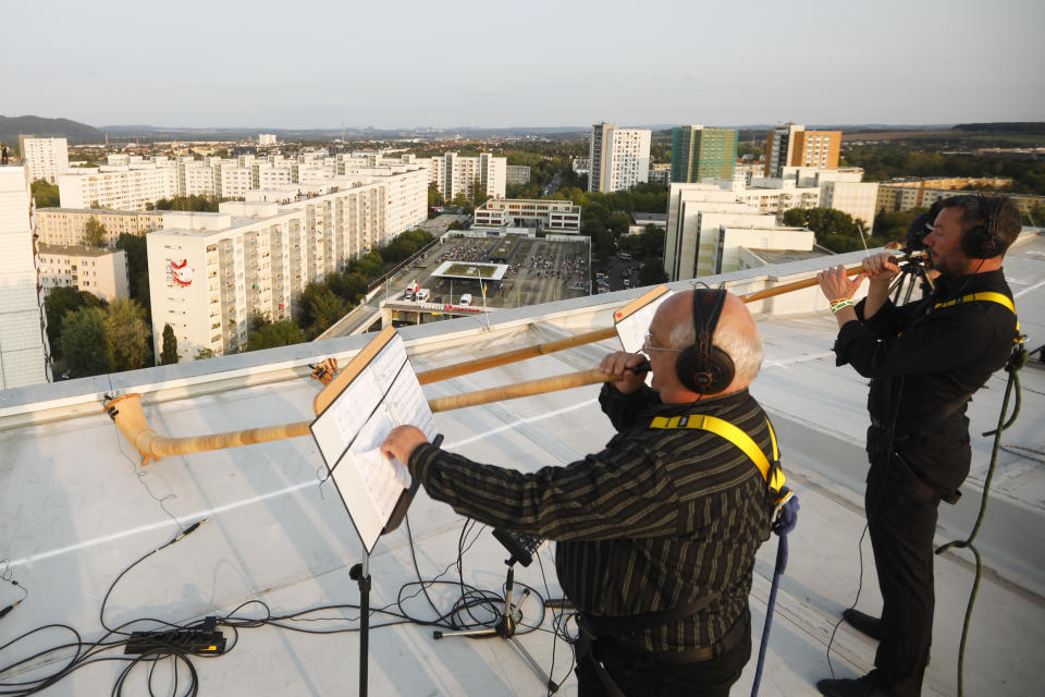 A musician with alp horns perform on the roof of an apartment block for a concert featuring distant harmonies, at a time when cultural events have been disrupted by the coronavirus pandemic, in the Prohlis neighborhood in Dresden, Germany, Saturday, Sept. 12, 2020. About 33 musicians of the Dresden Sinfoniker perform a concert named the 'Himmel ueber Prohils', The Sky above Prohlis, on the roof-tops of communist-era apartment blocs in the Dresden neighborhood Prohlis. (AP Photo/Markus Schreiber)