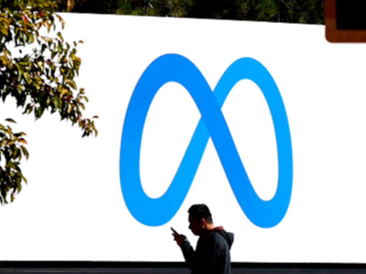 An employee stands under a sign for Meta, the company that owns Facebook  (Getty Images)