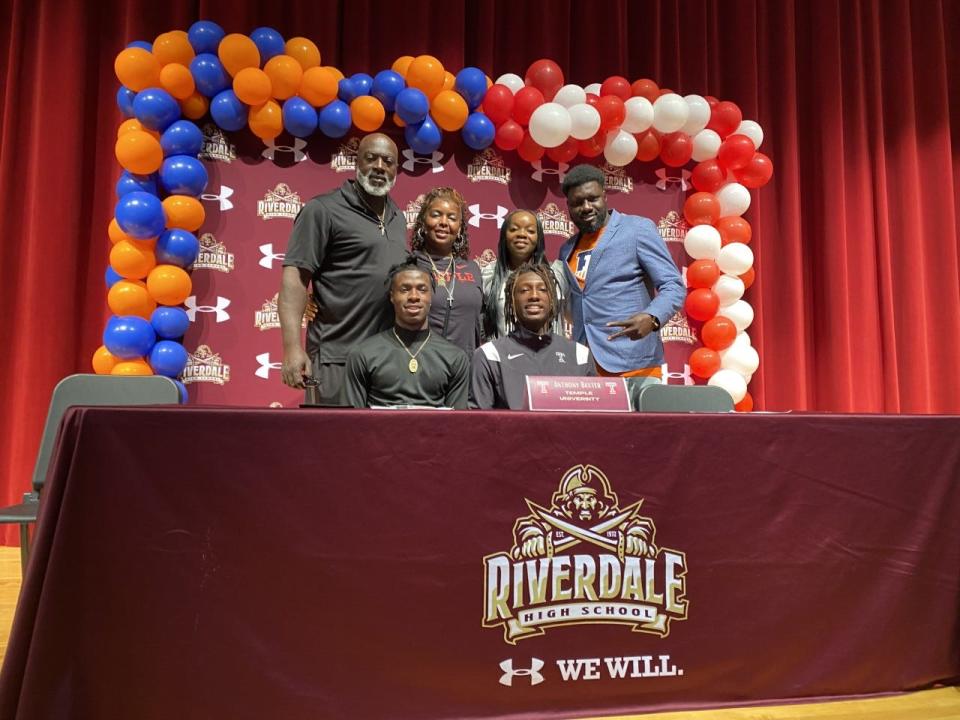 Riverdale defensive backs Jaheim Clarke and Anthony Baxter pose with their families after signing their letters of intent on December 21, 2022.