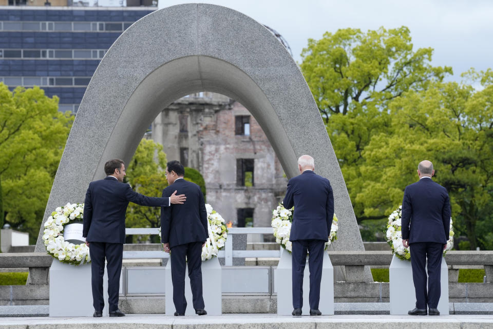 President Emmanuel Macron, left, of France gestures to Prime Minister Fumio Kishida of Japan after laying a wreath at the Hiroshima Peace Memorial Park with U.S. President Joe Biden and Chancellor Olaf Scholz, right, of Germany in Hiroshima, Japan, Friday, May 19, 2023, during the G7 Summit. (AP Photo/Susan Walsh,Pool)