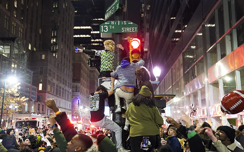 Philadelphia Eagles supporters climb a light post