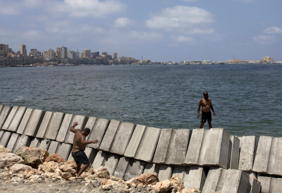 In this Aug. 8, 2019, photo, workers prepare to place cement blocks to reinforce the sea wall against rising water levels on the corniche in Alexandria, Egypt. Alexandria, which has survived invasions, fires and earthquakes since it was founded by Alexander the Great more than 2,000 years ago, now faces a new menace from climate change. Rising sea levels threaten to inundate poorer neighborhoods and archaeological sites, prompting authorities to erect concrete barriers out at sea to hold back the surging waves. (AP Photo/Maya Alleruzzo)