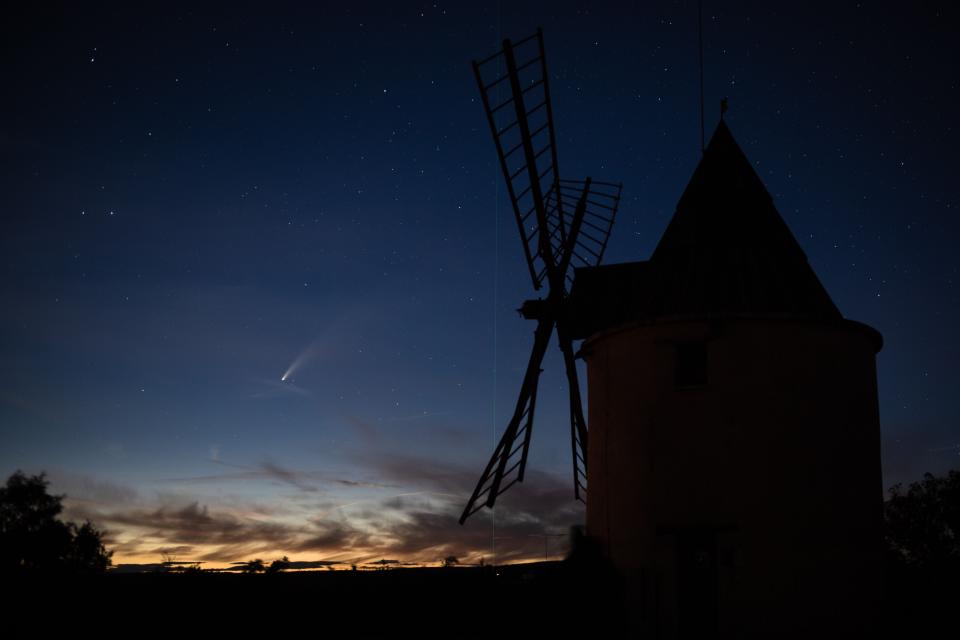 A picture taken on July 15, 2020, shows Comet Neowise and the green laser beam used by the Haute-Provence Observatory to point celestial objects for studies and researches, with an old windmill in the foreground in Saint-Michel-L'Observatoire, southern France.