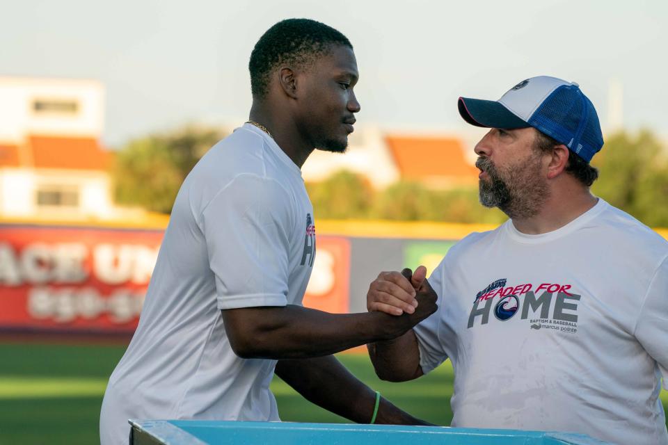 Blue Wahoos catcher Paul McIntosh is congratulated by a church member at Marcus Pointe Baptist Church after being baptized with more than 20 others in a special post-game, baptismal Sunday at Blue Wahoos Stadium.