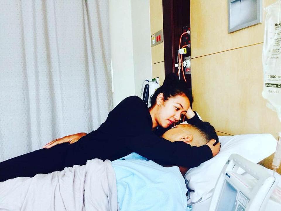 Sarah Pene cradles her husband, Harvee Pene, in a hospital bed after he was diagnosed with testicular cancer. 