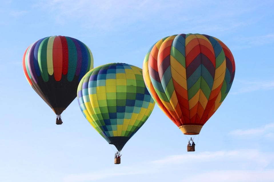 Three colorful hot air balloons sail over the Balloon and Wine Festival via Getty Images/ Karol Franks