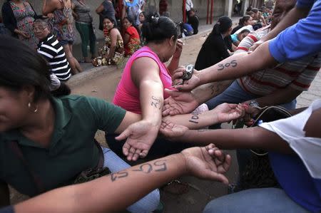 People show numbers written on their arms with the order they should enter at the state-run Bicentenario supermarket in Maracaibo January 11, 2015. REUTERS/Isaac Urrutia