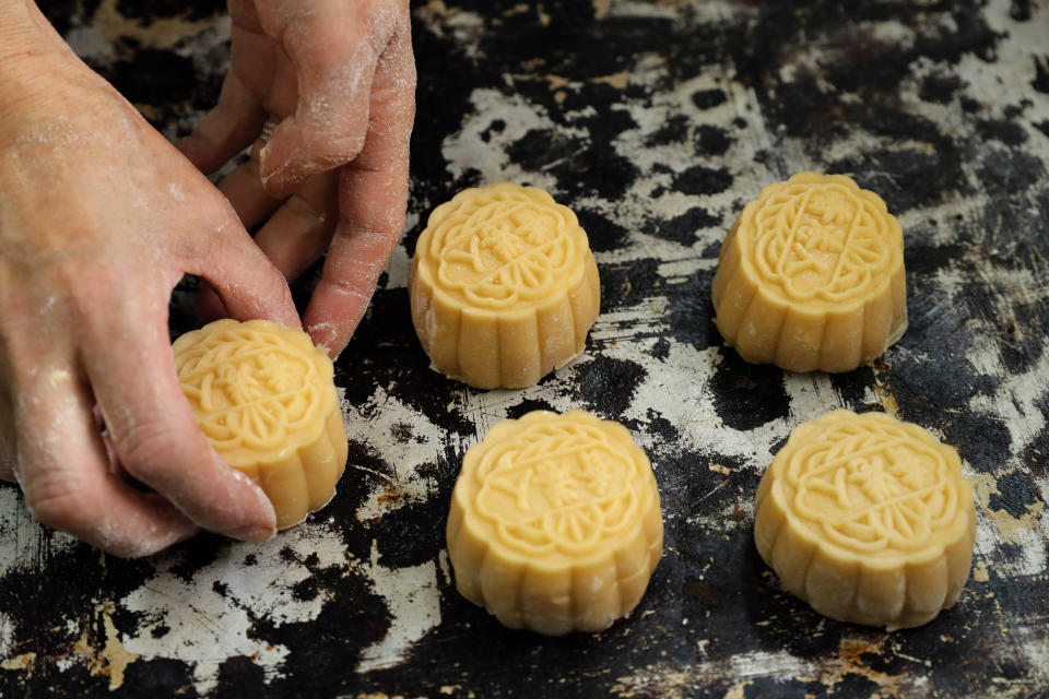 In this Friday, Aug. 9, 2019 photo, a staff member places mooncakes with Chinese words "Hong Kong people" on the tray at Wah Yee Tang bakery in Hong Kong. This year, At Wah Yee Tang, the traditional Chinese harvest festival treat comes with a twist: slogans opposing the city’s Beijing-backed government and promoting Hong Kong’s unique identity that have become popular rallying cries during the protests. Mooncakes are stamped with the messages such as "No withdrawal, no dispersal", "Be water", and "Hong Kong people". (AP Photo/Kin Cheung)