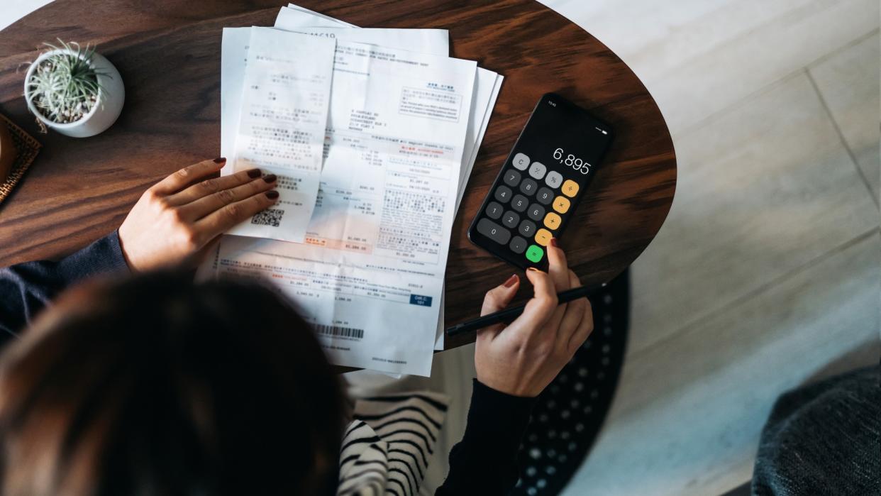  Person sitting at a table with papers and a calculator. 