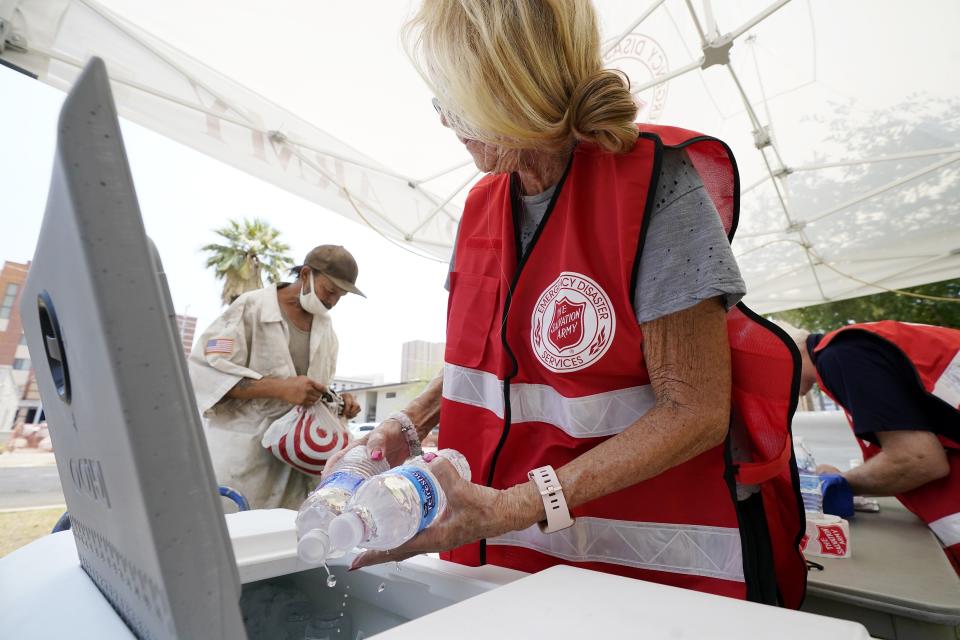 Salvation Army hydration station volunteer Kathleen McAllister, right, hands out water during a heatwave sending temperatures above 115-degrees, Tuesday, June 15, 2021, in Phoenix. (AP Photo/Ross D. Franklin)
