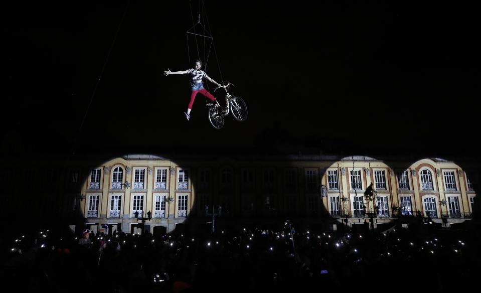An artist performs above spectators during a mapping and pyrotechnics show coined "Closer to the stars" as part of the holiday season festivities at Bolivar square in Bogota, Colombia, on Sunday, Dec. 16, 2018. (AP Photo/Fernando Vergara)