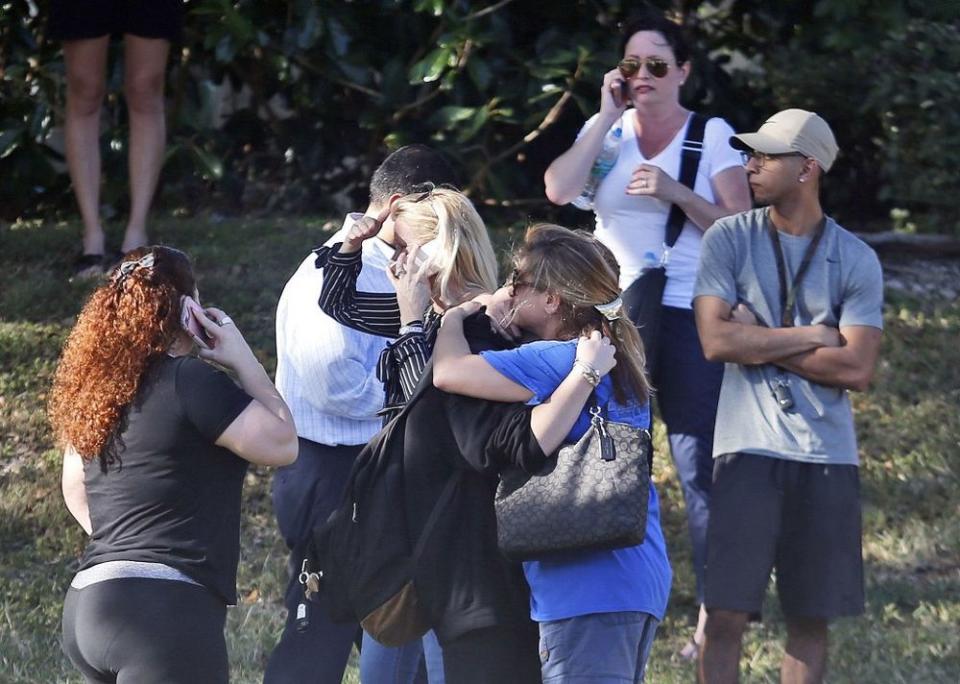 Anxious family members wait for news of students as two people embrace, in Parkland, Fla.