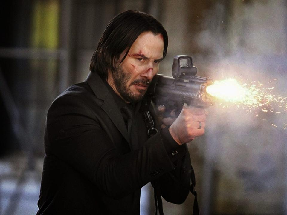 Keanu Reeves as John Wick shooting a shotgun.