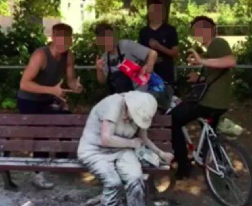 <em>A group of teenagers pictured above the woman, who was cowering after being pelted with eggs and flour (Picture: Facebook)</em>